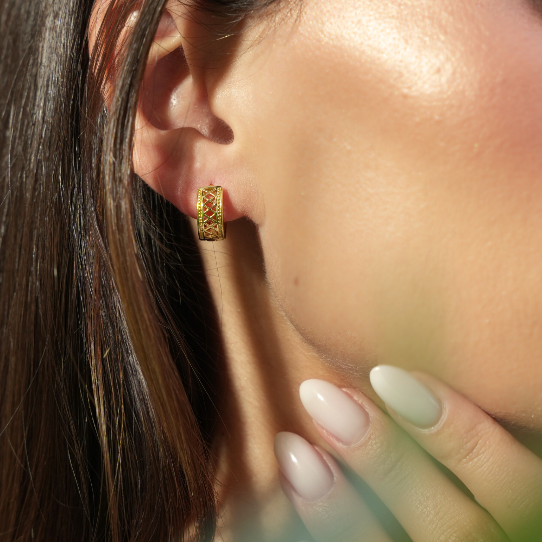 Close-up of a person wearing a gold earring with a blurred background