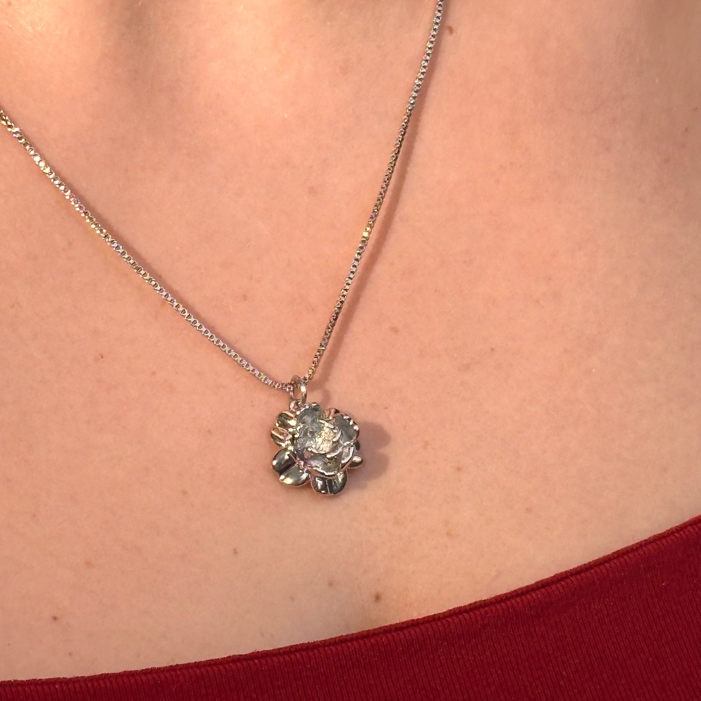 Necklace with a pendant worn by a person against a neutral background