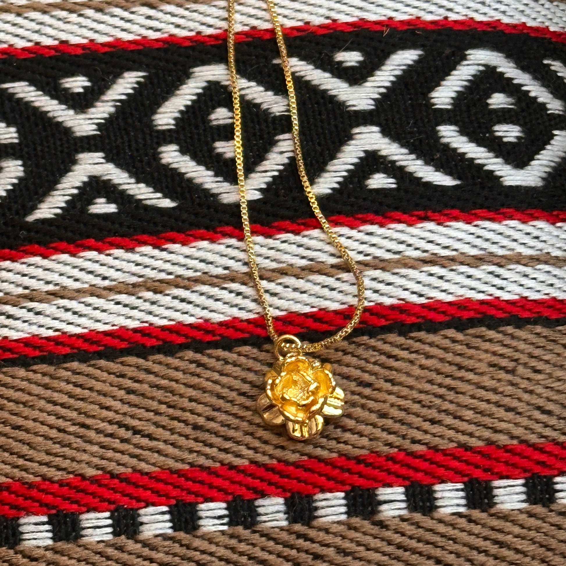 Gold necklace with a decorative clasp on a patterned fabric background