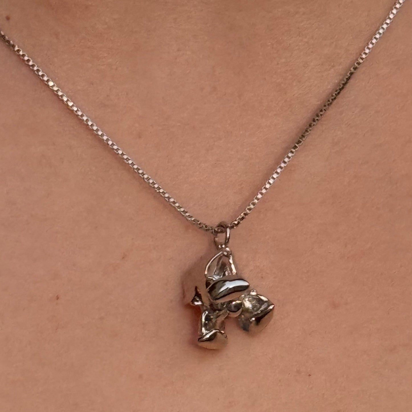 Silver necklace with a pendant on a person's neck against a red garment background