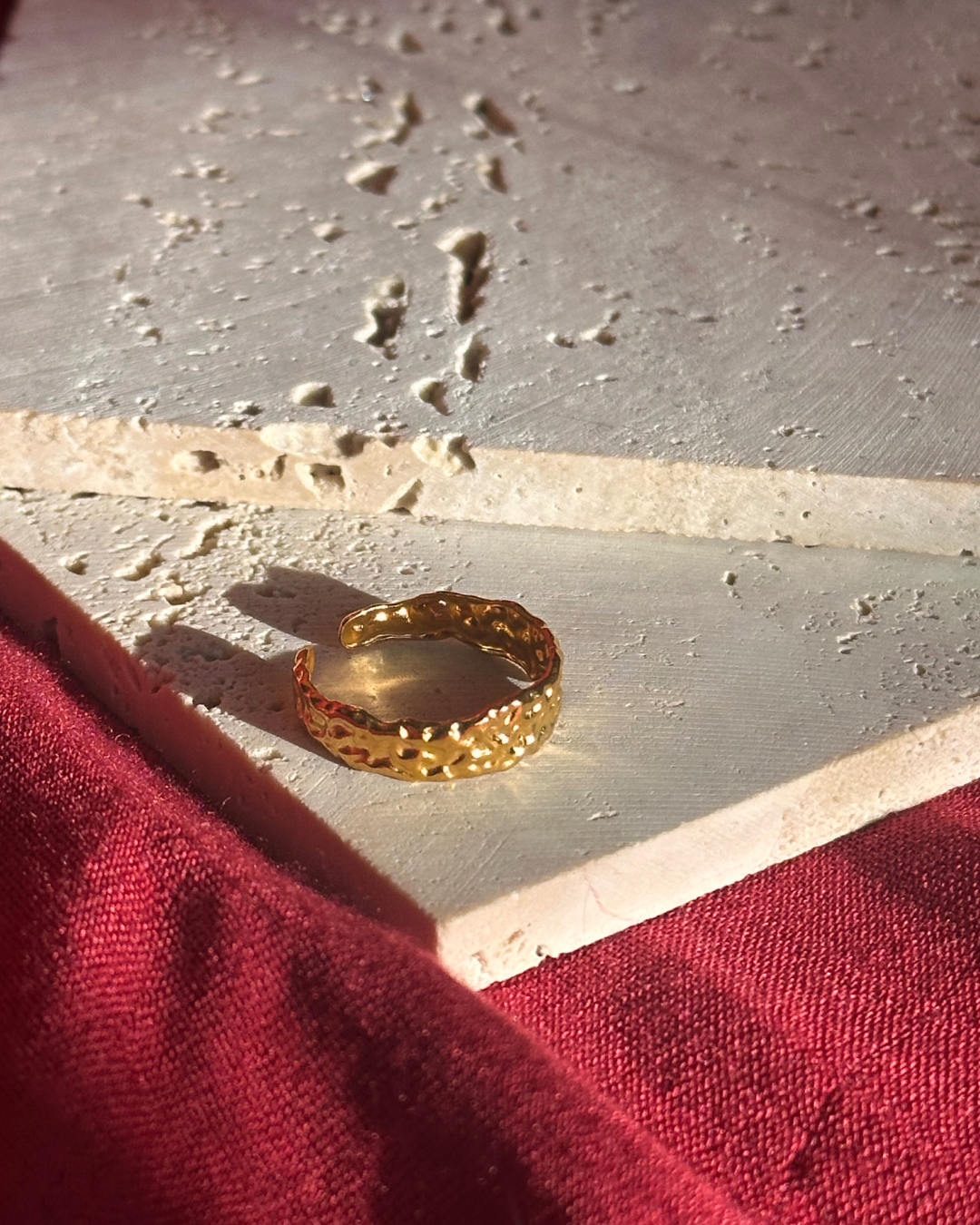 Gold ring on a textured surface with red fabric