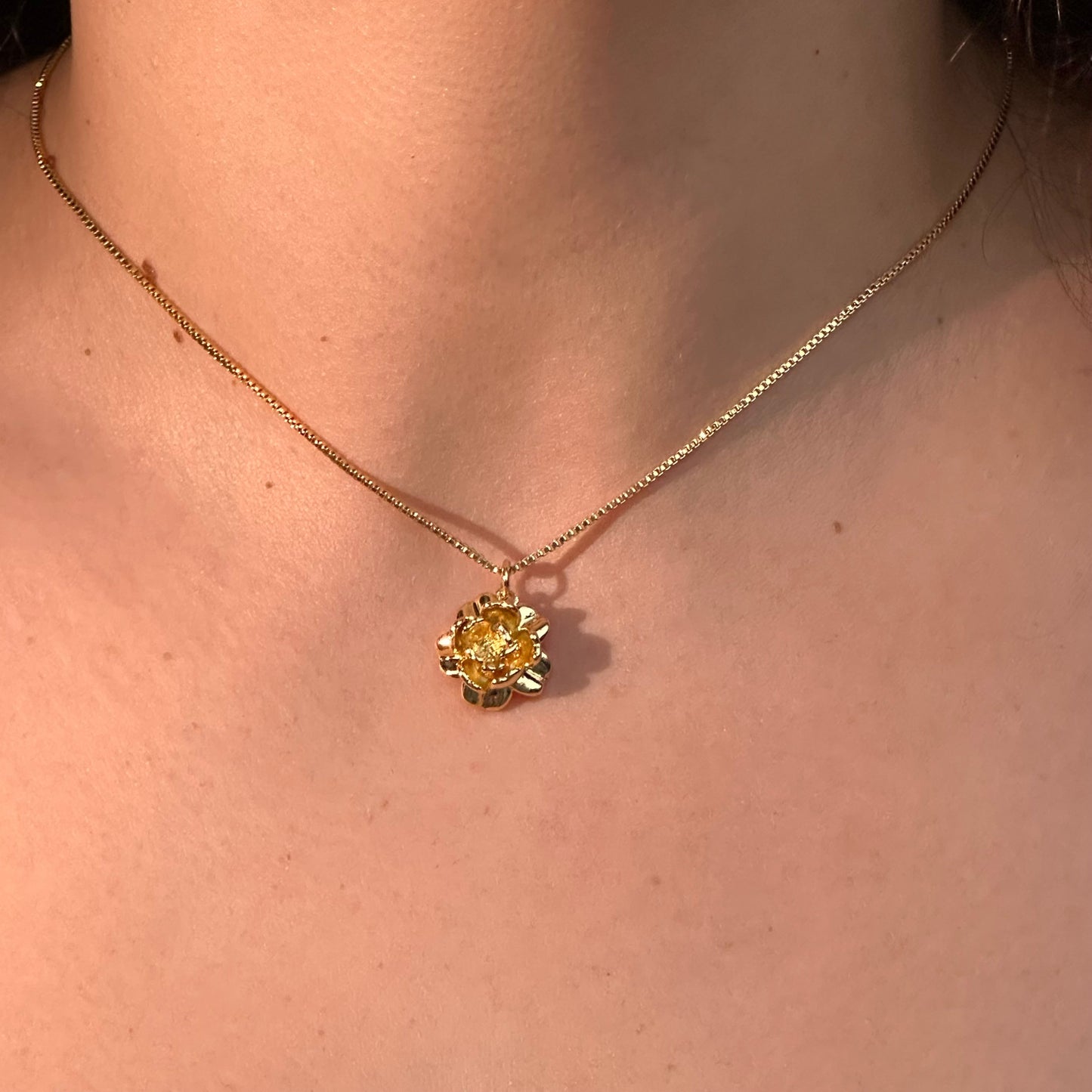 Gold necklace with a yellow pendant on a person's neck